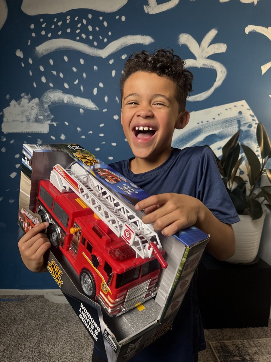 Bryson smiling with a toy fire truck